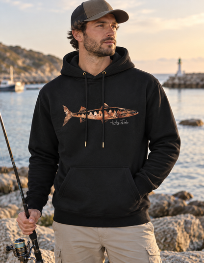 Angler am Meer trägt schwarzen Holy Fish M9 Barracuda-Hoodie mit kupferfarbenem Brustmotiv